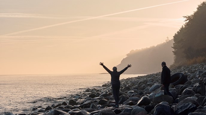 Pensioneret kvinde og mand nyder aftensolen ved solnedgang på stranden