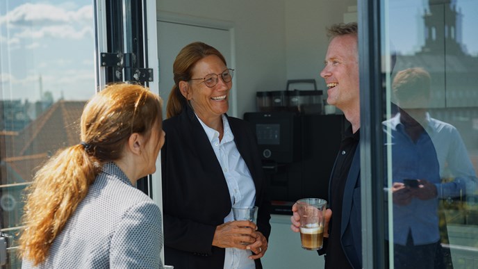 Tre pensionsrådgivere har en samtale over en kop kaffe på en altan i København