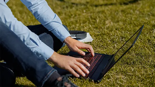 Mand sidder på græsset med sin computer
