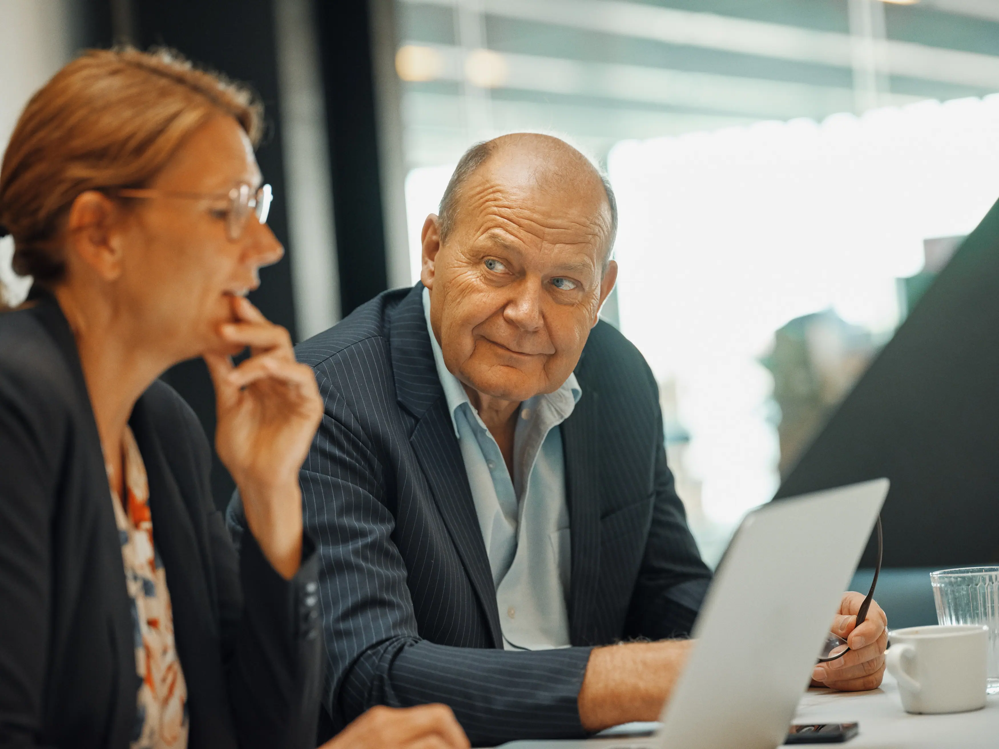 To pensionsrådgivere kigger på hinanden, mens de sidder ved en computer
