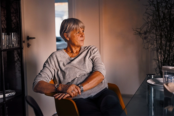 Seniorliv kvinde sidder og kigger i sin spisestue